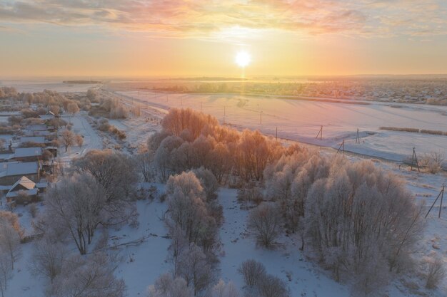 Photo le gel dans les arbres à l'aube le soleil se lève sur les champs dans la neige vue aérienne
