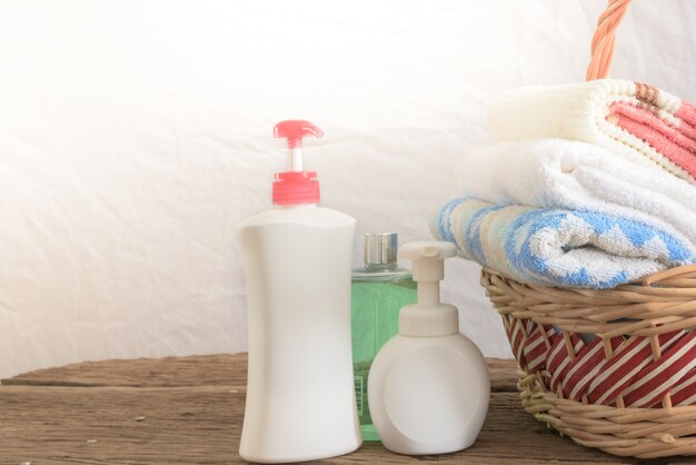 Gel douche avec crème pour la peau et serviettes de bain dans le panier sur la table en bois