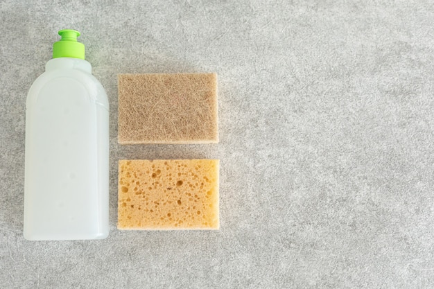 Gel lave-vaisselle biodégradable et éponge en mousse sur une table en pierre. Le concept de nettoyage et de maintien de la propreté.