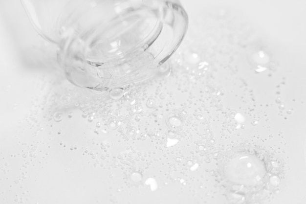 Gel ou liquide transparent avec des bulles s'écoulant de la bouteille sur le fond