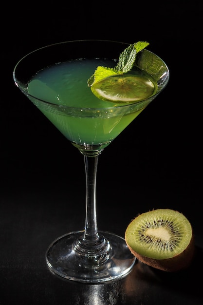 Gelée de kiwi avec des morceaux de citron vert dans les feuilles de menthe surmontées de verre sur fond noir