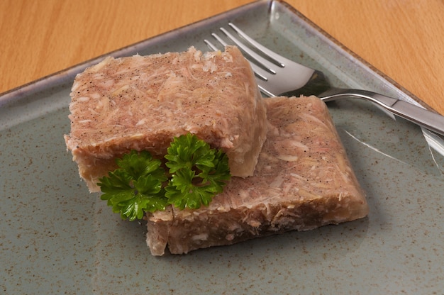 Gelée de viande décorée de légumes verts sur une assiette close up