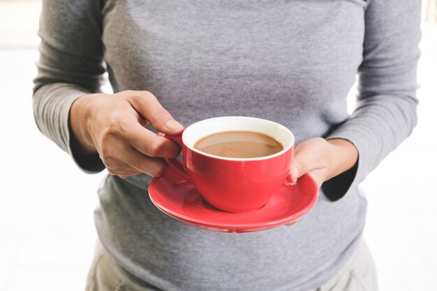 Gène féminin tenant une tasse de café rouge