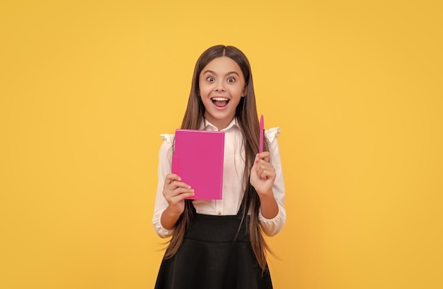 Génie de l'enfant heureux tenir le livre d'école pointant le stylo vers le haut idée de fond jaune