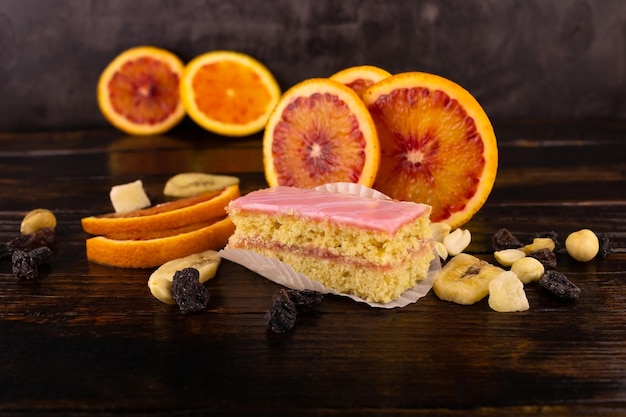 Génoise En Glaçage Rose Avec Des Tranches D'orange Rouge Et Une Dispersion De Fruits Secs Et De Noix