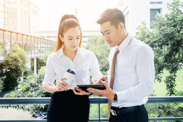 Gens d&#39;affaires asiatiques réunion et utilisation de tablette numérique en plein air après le travail