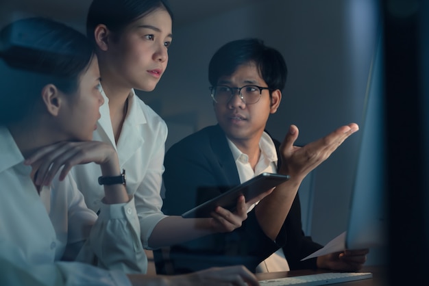 Les gens d'affaires asiatiques travaillent dur tard ensemble et la planification avec l'ordinateur de bureau dans la nuit