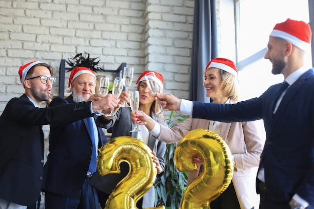 Les gens d'affaires célèbrent les vacances dans un bureau moderne en buvant du champagne et en s'amusant dans le coworking. Joyeux Noël et bonne année 2022.