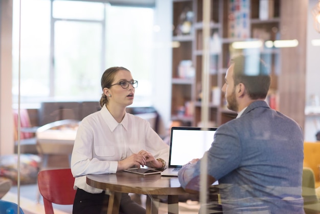 des gens d'affaires en démarrage utilisant un ordinateur portable se préparant pour la prochaine réunion et discutant d'idées dans un bureau créatif