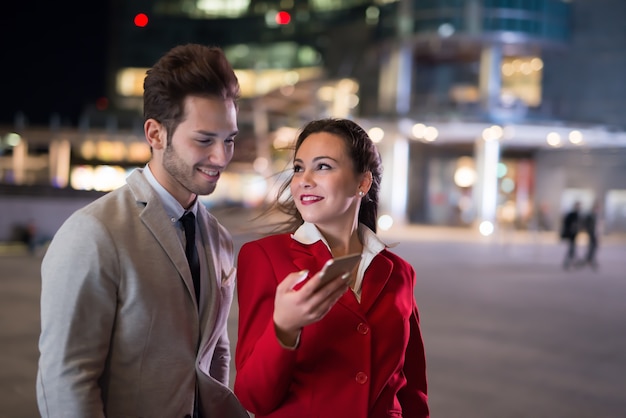 Gens d'affaires homme d'affaires et femme d'affaires à l'aide d'un smartphone la nuit dans une ville