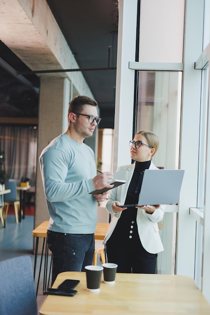 Gens d'affaires homme et femme autour d'un café discutant d'affaires regardant un ordinateur portable espace de travail moderne Collègues travaillent ensemble au bureau