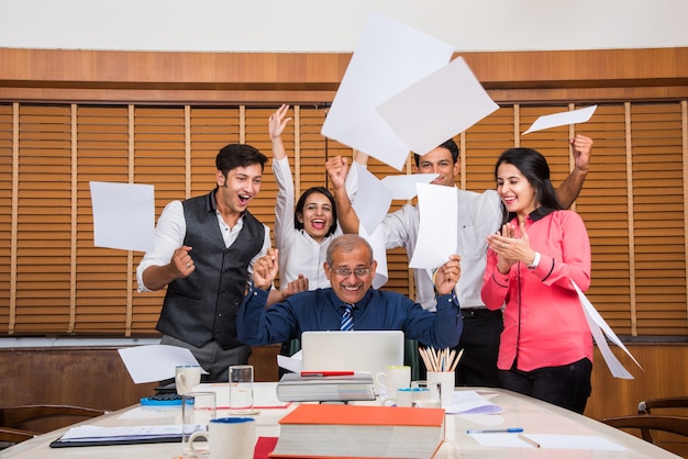 Gens d'affaires indiens ou culture d'entreprise et travail au bureau Concept avec ordinateur portable, papiers, réunions célébrant le succès ou la victoire