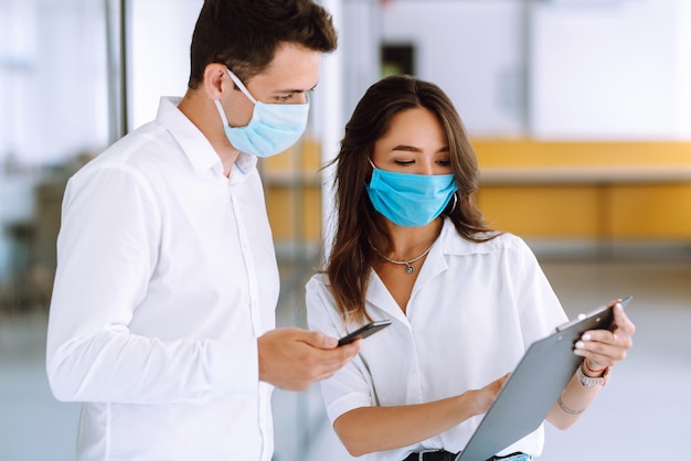 Gens d'affaires avec masque facial travaillant au bureau. Le concept de prévention de la propagation de l'épidémie.