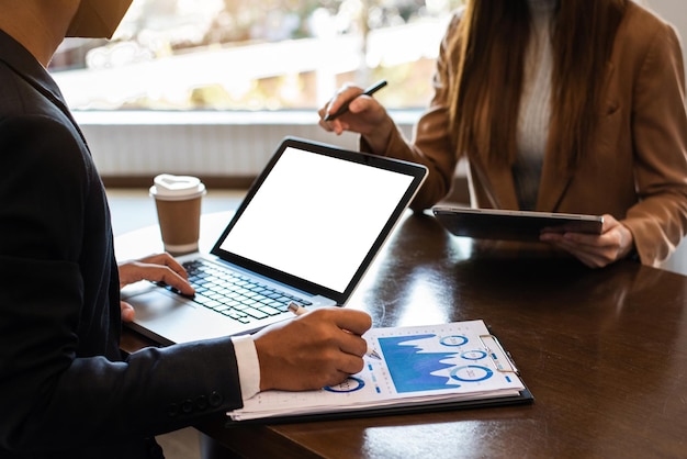 Gens d'affaires parlant discutant avec des tableaux et des graphiques de données de documents financiers Réunion d'affaires d'équipe avec un téléphone intelligent, un ordinateur portable et une tablette numérique xA