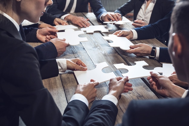 Gens d'affaires et puzzle sur table en bois, concept de travail d'équipe