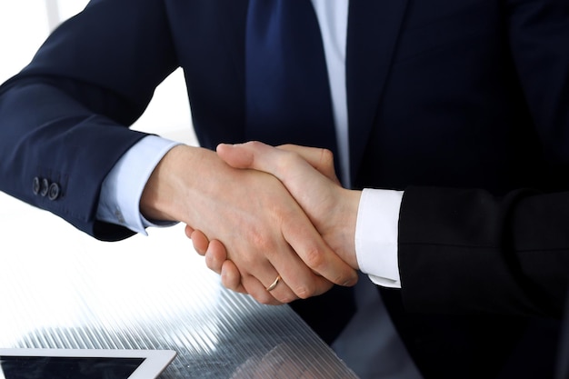 Gens d'affaires se serrant la main après la signature du contrat au bureau en verre dans un bureau moderne