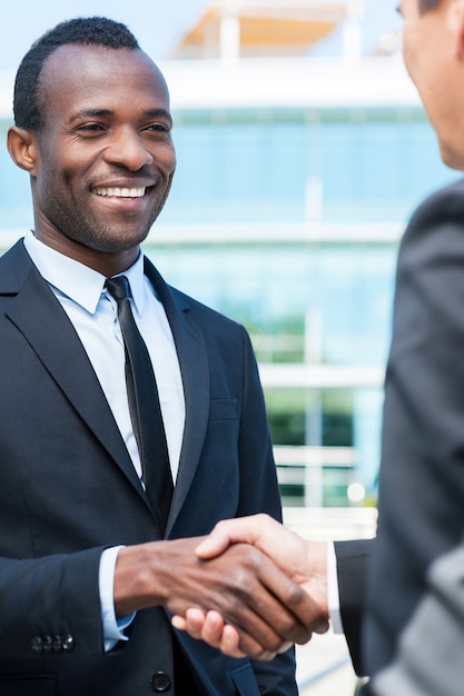 Les gens d'affaires se serrant la main. Deux hommes d'affaires se serrant la main et souriant tout en se tenant à l'extérieur