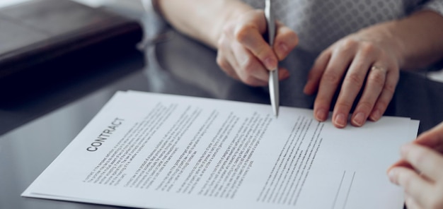 Gens d'affaires signant des documents contractuels assis à la table en verre au bureau, en gros plan. Partenaires ou avocats travaillant ensemble lors de la réunion. Travail d'équipe, partenariat, concept de réussite.