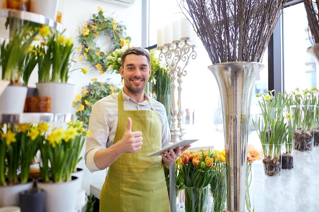 les gens, les affaires, la technologie, la vente et la fleuristerie et le concept - un fleuriste souriant et heureux avec un ordinateur tablette au fleuriste