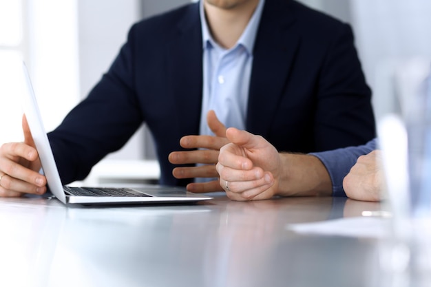 Gens d'affaires utilisant un ordinateur portable tout en travaillant ensemble au bureau dans un bureau moderne