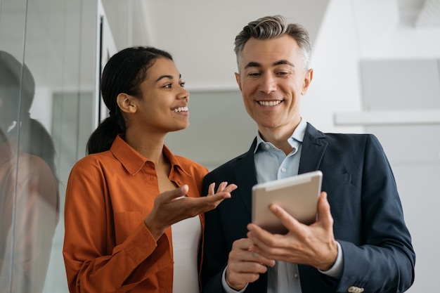 Les gens d'affaires utilisant la planification de la tablette numérique démarrent, partageant des idées sur le lieu de travail.