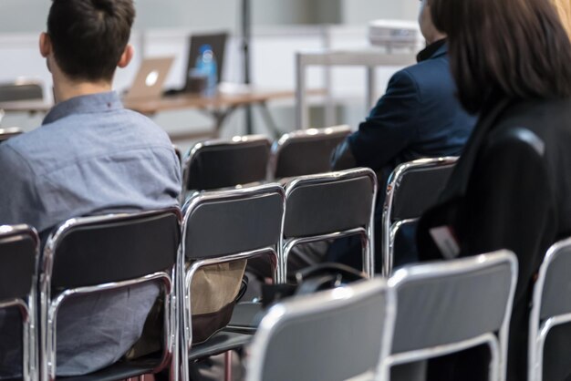 Des gens assis sur des chaises dans une salle de séminaire lors d'une réunion de présentation d'entreprise