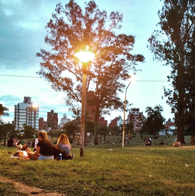 Photo des gens assis dans un parc par ville contre le ciel au coucher du soleil