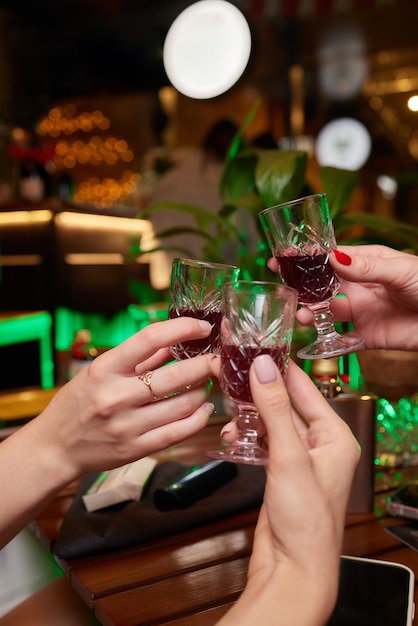 Les gens au bar essaient des teintures des teintures rouges dans des verres des shots alcoolisés