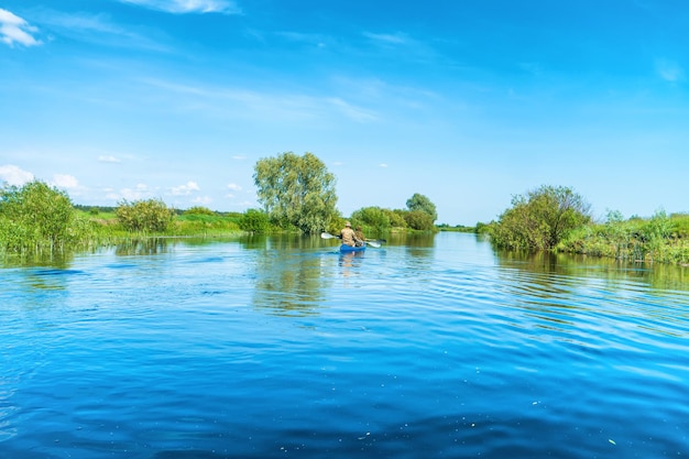 Les gens au voyage en kayak sur le paysage de la rivière bleue et la forêt verte avec des arbres ciel bleu nuages eau