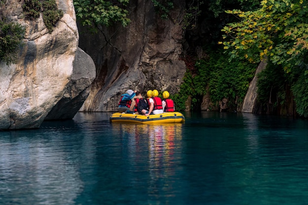 Les gens sur un bateau gonflable flottent dans un canyon rocheux avec de l'eau bleue à Goynuk Turquie