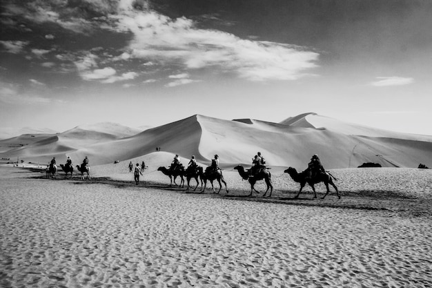 Photo des gens à cheval sur des chameaux dans le désert contre le ciel