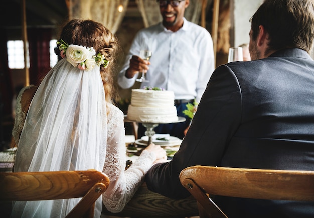 Les gens collent des verres de vin sur la réception de mariage avec les jeunes mariés