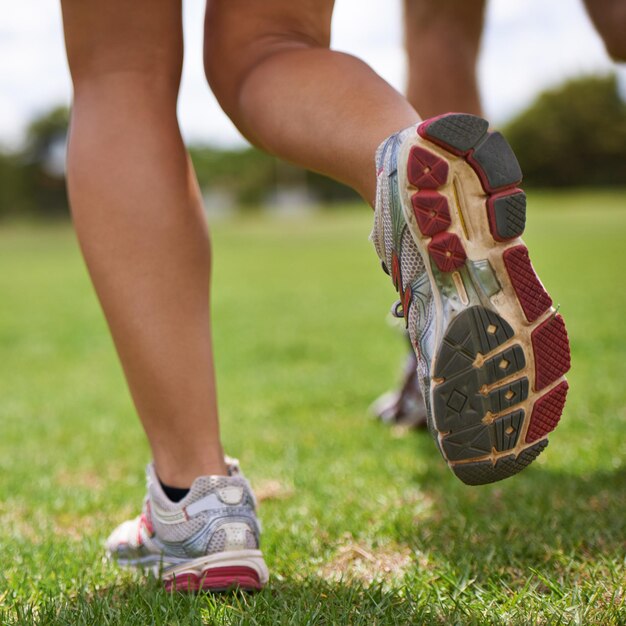 Photo les gens courent avec des chaussures et un gros plan sur l'herbe pour l'exercice ensemble en été pour la santé, le bien-être ou l'entraînement.