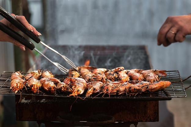 les gens cuisinent de grosses langoustines sur le gril dans la cour