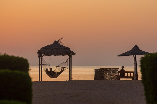 des gens dans des hamacs et des bancs qui attendent le lever du soleil sur la mer Rouge en Égypte