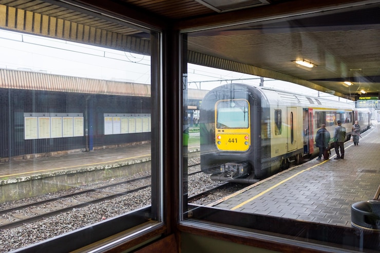 Photo des gens dans le train sur la plate-forme de la gare vus à travers une fenêtre en verre