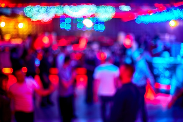 Les gens dansent chanter s'amuser et se détendre dans un arrière-plan flou de boîte de nuit. Flashs de lumière Belles lumières floues sur la piste de danse se détendre la nuit dans le club