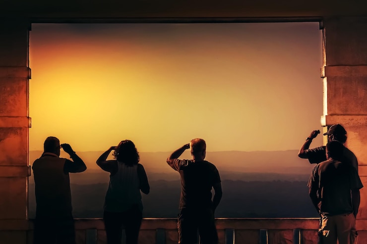 Photo des gens debout à un point d'observation contre le ciel au coucher du soleil