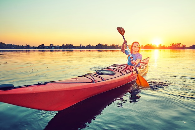 Les gens font du kayak pendant le coucher du soleil en arrière-plan. Amusez-vous pendant votre temps libre.