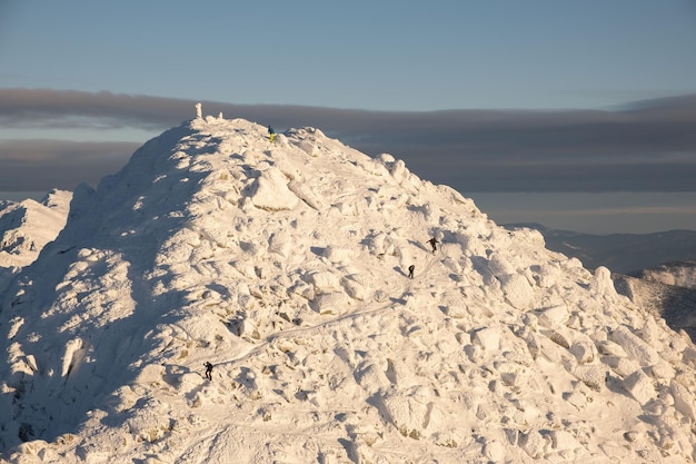 Les gens grimpent au sommet des montagnes enneigées