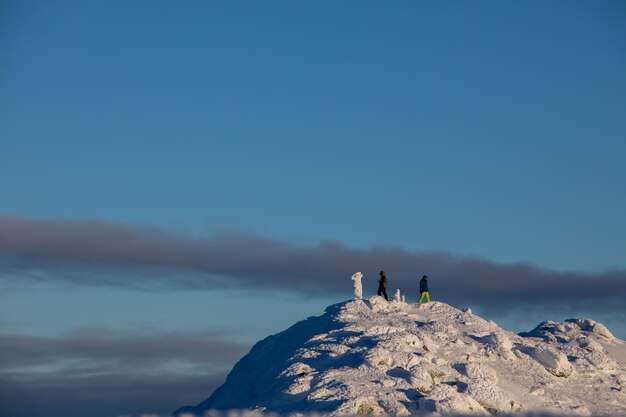 Les gens grimpent au sommet des montagnes enneigées