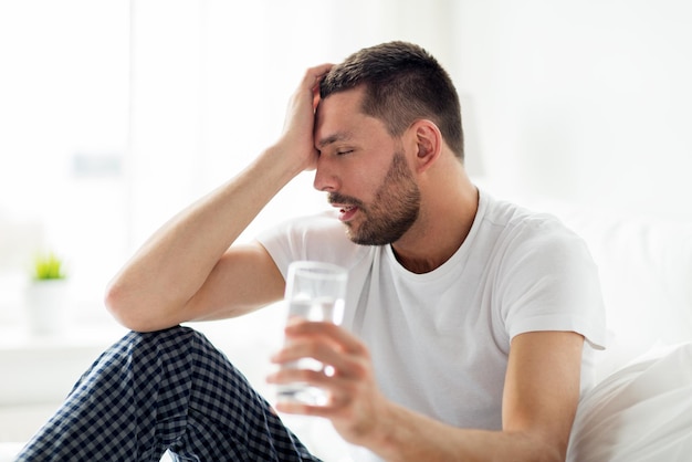 les gens, l'heure du coucher et le concept de repos - l'homme au lit avec un verre d'eau à la maison