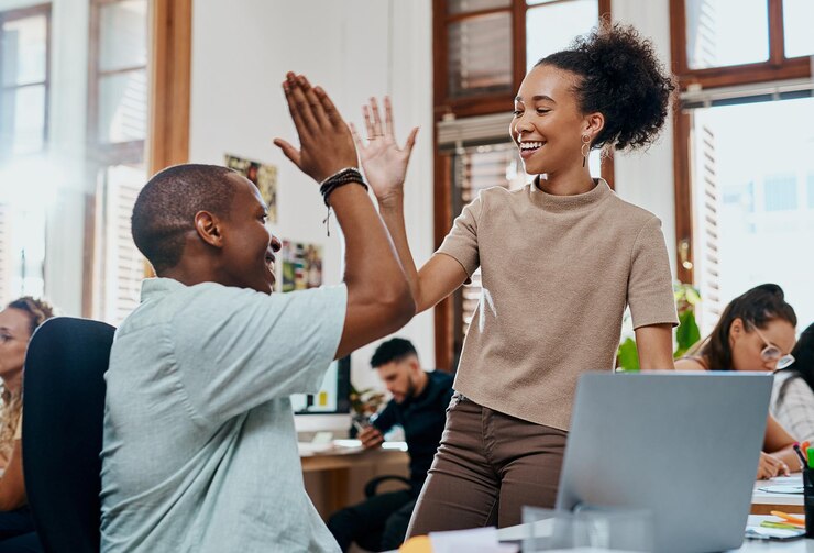 Photo les gens heureux affaires et ordinateur portable avec high five pour le succès du travail d'équipe ou la victoire au bureau les jeunes employés ou collègues excités pour la motivation la collaboration ou la promotion sur l'ordinateur sur le lieu de travail