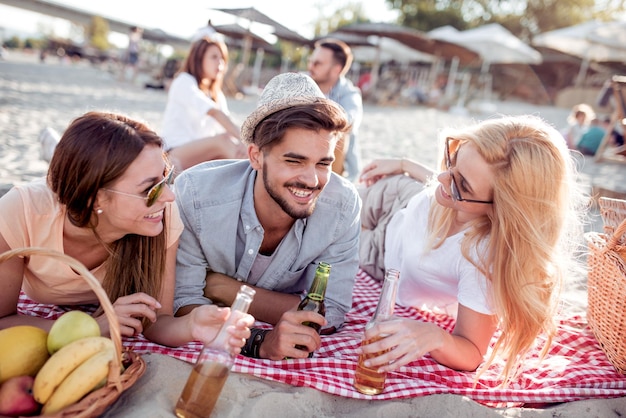 Gens heureux buvant de la bière sur la plage