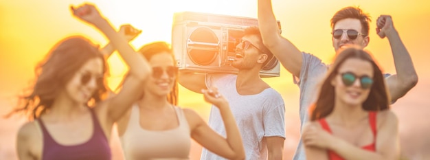 Les gens heureux dansant avec un boom box sur le fond ensoleillé