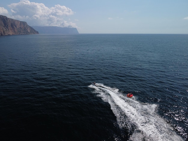 Des gens heureux nagent sur un matelas pneumatique derrière un vélo aquatique à grande vitesse, les touristes montent sur un bateau gonflable