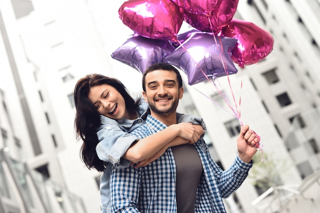 Des gens heureux ont un rendez-vous dans la ville tenant des ballons.