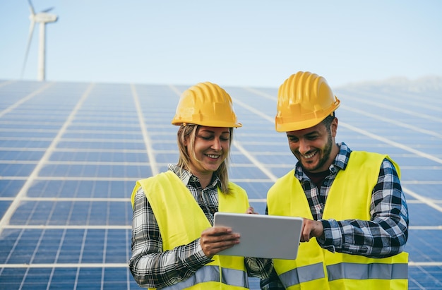 Des gens heureux travaillant avec une tablette numérique dans une ferme d'énergie renouvelable se concentrent sur le visage de la femme