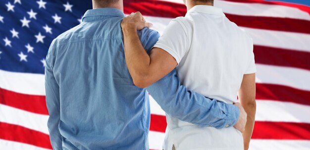 Photo les gens, l'homosexualité, le mariage homosexuel, le concept gay et amoureux - gros plan d'un couple gay masculin heureux ou d'amis se serrant de dos sur fond de drapeau américain