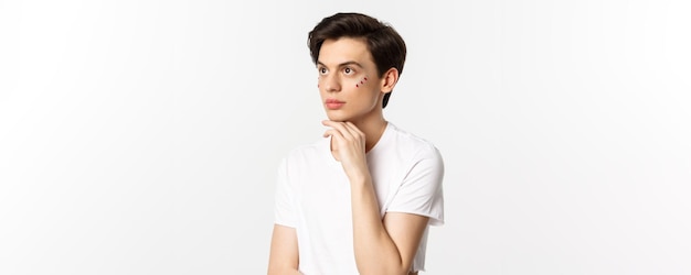 Les gens lgbtq et le concept de beauté bel homme androgyne avec des paillettes sous les yeux regardant la partie supérieure